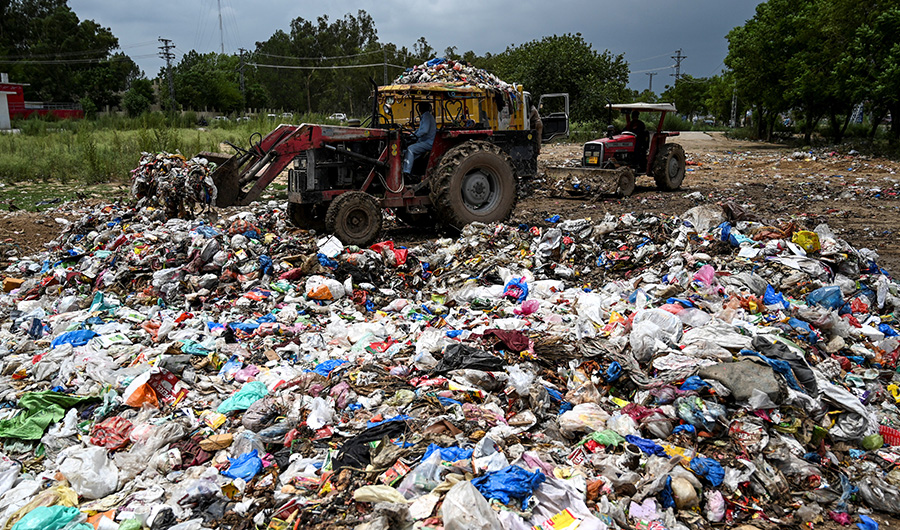 In this picture taken on July 16, 2019, municipal workers load garbage into a dump truck at a trash site full of plastic bags in Islamabad. (AFP)