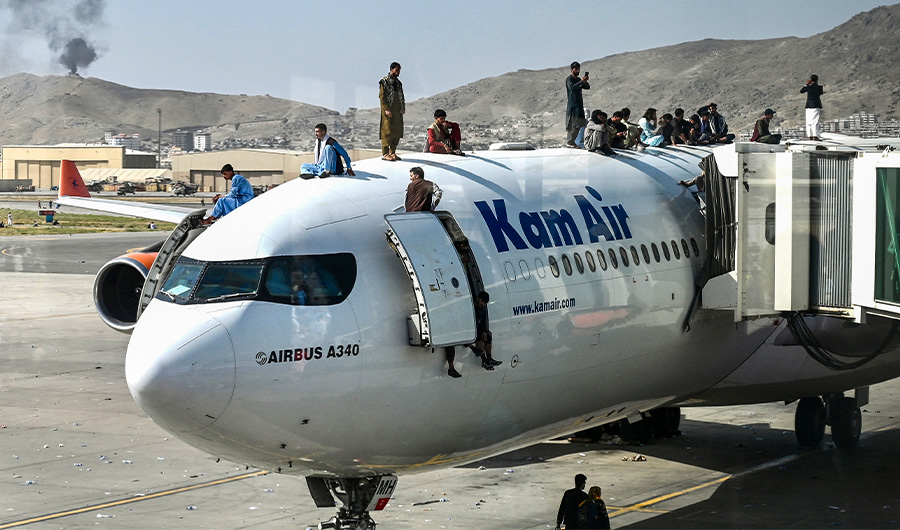 Afghan people climb atop a Kam Air (the largest private Afghan airline) plane as they wait at the airport in Kabul on August 16, 2021. (AFP)