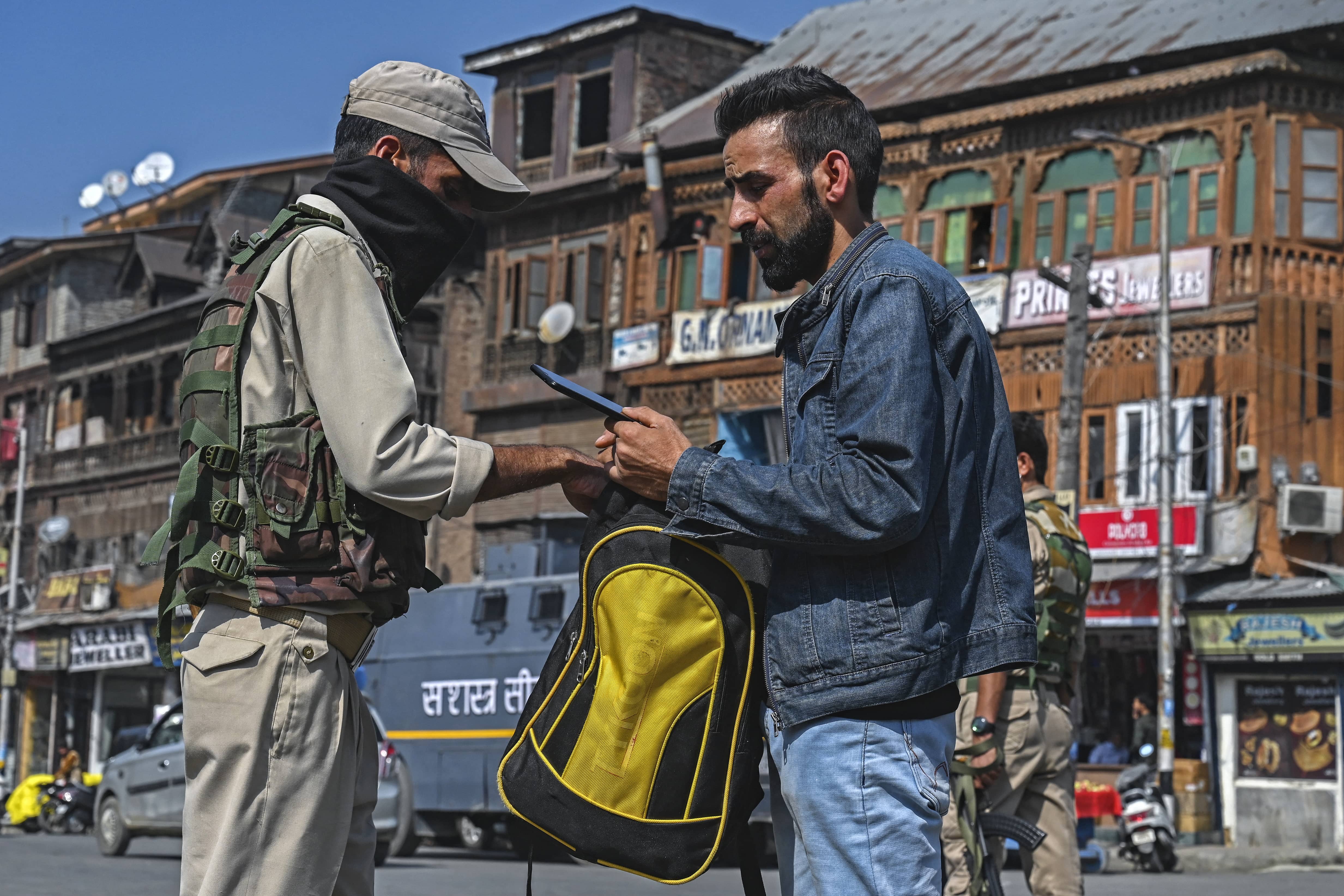 A security personnel checks the bag of a pedestrian along a street in Srinagar on October 9, 2021. (AFP)