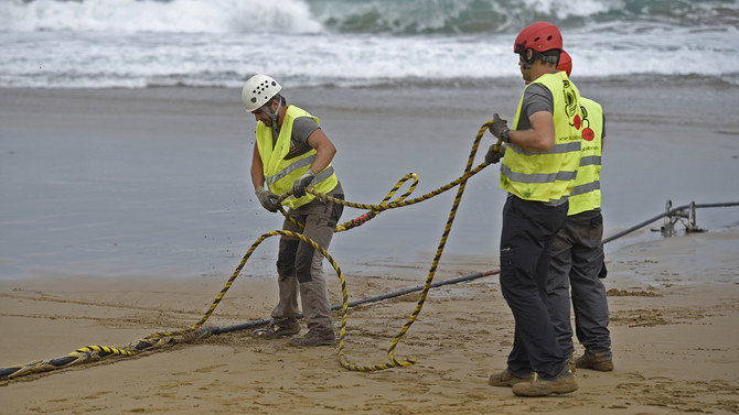 In this file photo, operators handle an undersea fiber optic cable at Arrietara beach near the Spanish Basque village of Sopelana on June 13, 2017. (AFP/File)