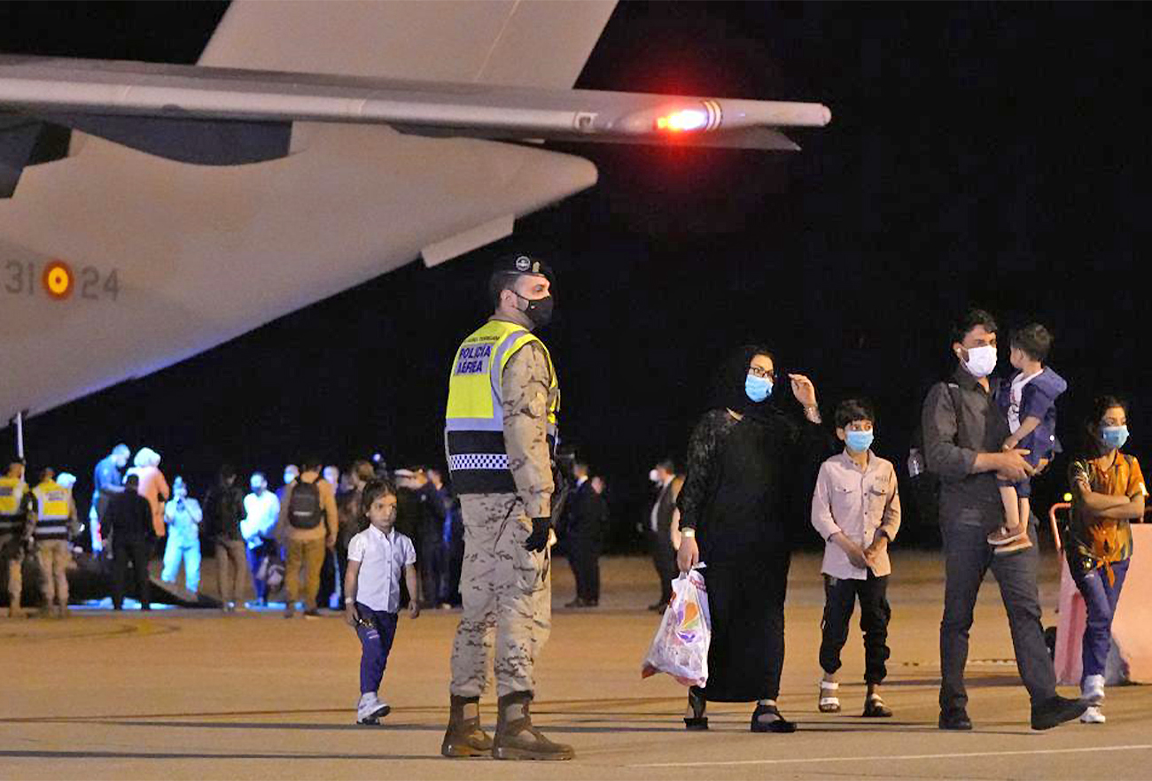 Afghan people who were transported from Islamabad, walk after disembarking a plane, at the Torrejon military base in Spain on October 11, 2021. (AP)