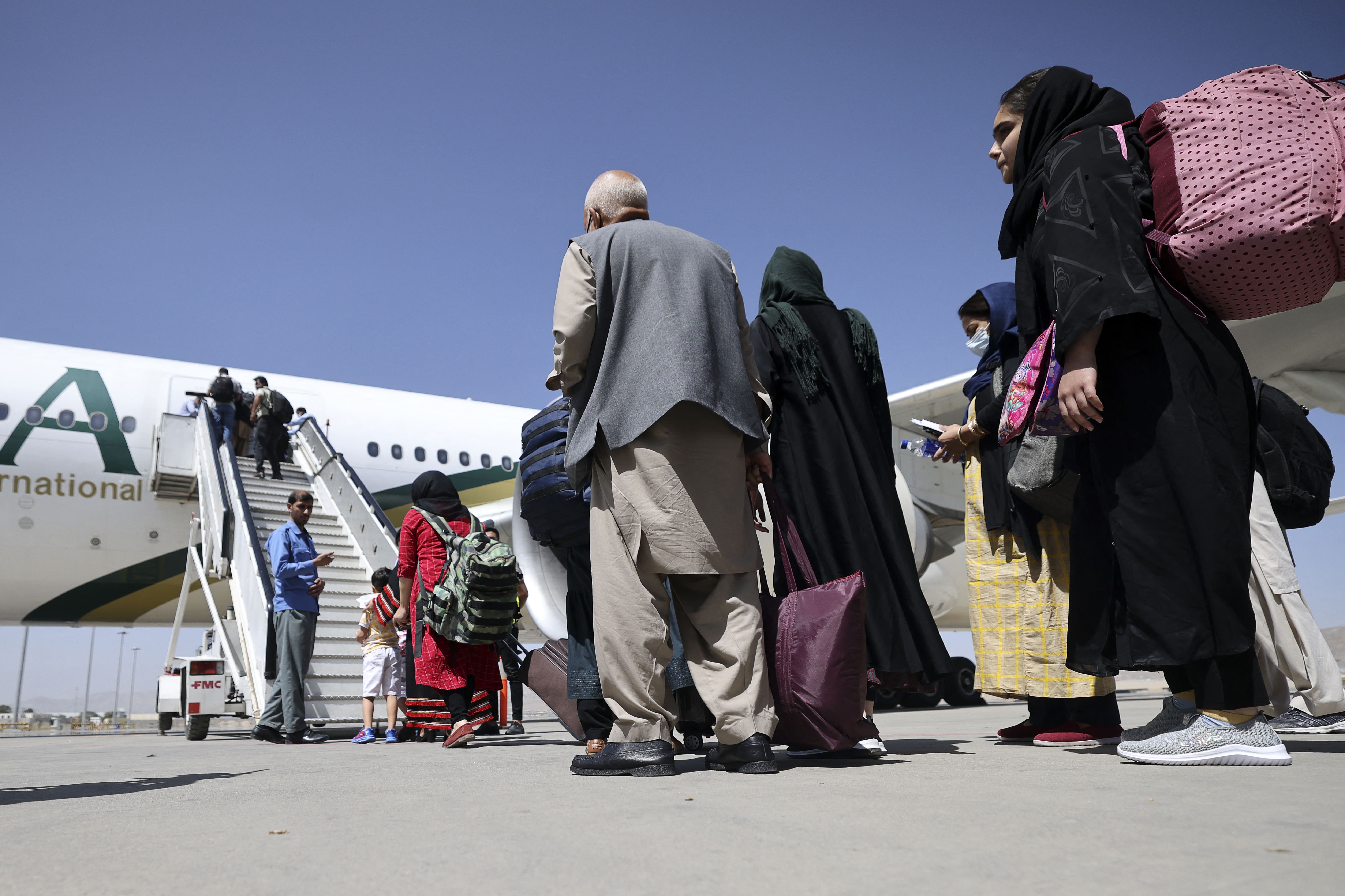 Passengers stand in a queue to board on a Pakistan International Airlines plane, which is the first international commercial flight to land since the Taliban retook power in Afghanistan on August 15, at the airport in Kabul on September 13, 2021. (AFP)