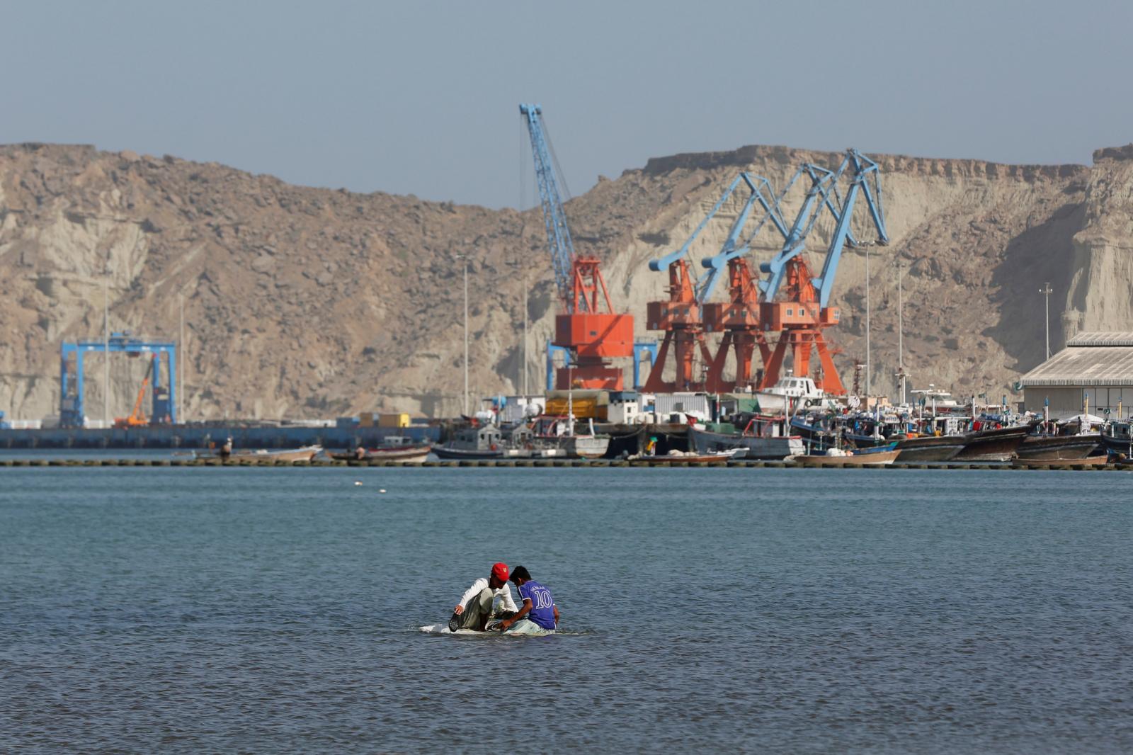 Boys sit on a piece of styrofoam sheet as they search for crabs in front of the Gwadar port, Pakistan, on April 11, 2017. (REUTERS)