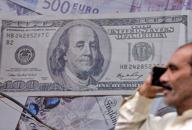 A Pakistan man talks on the phone in front of a poster displaying US dollars at the currency exchange place in Lahore, Pakistan, on May 16, 2019. (AFP/File)