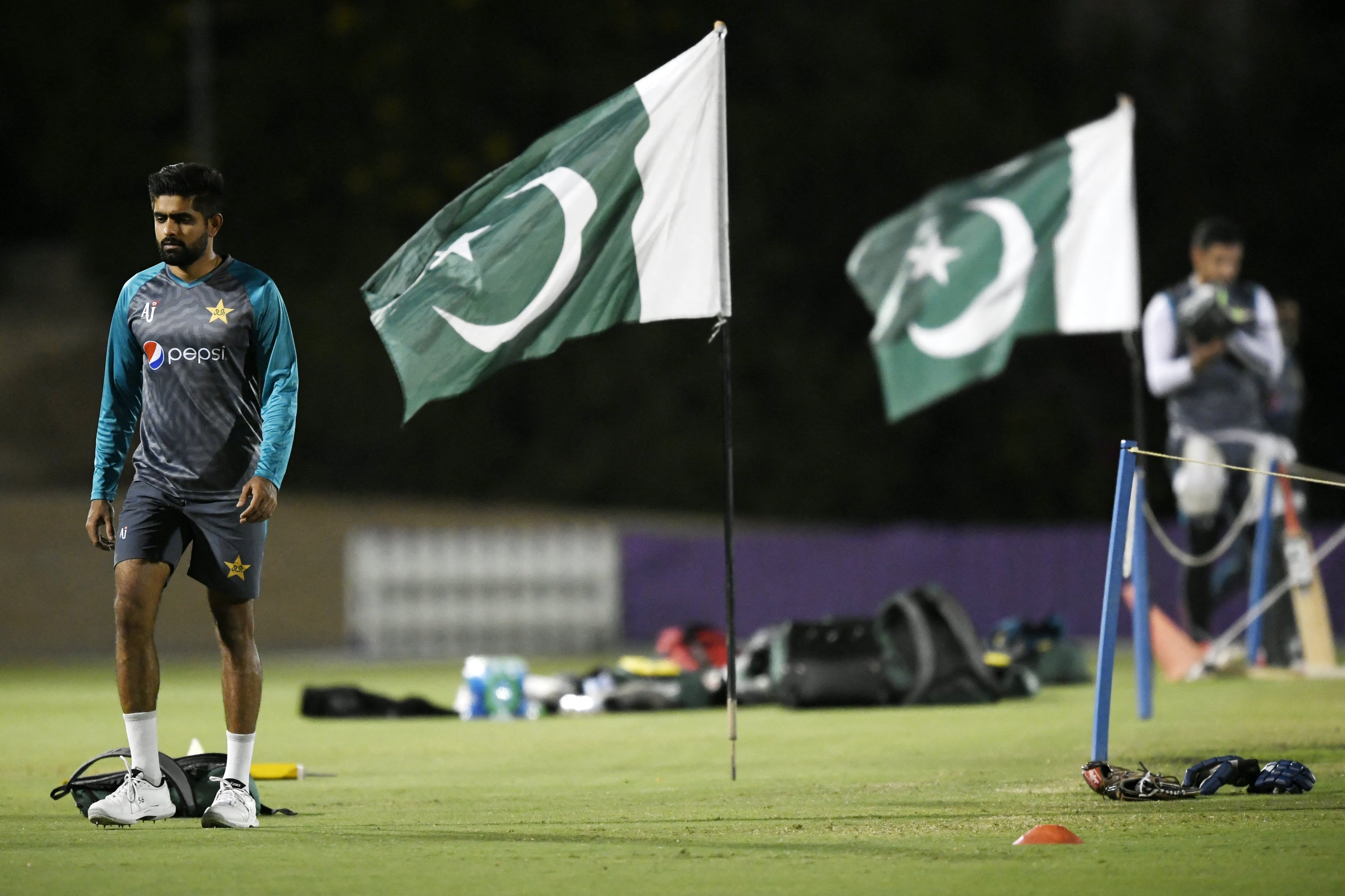 Pakistan's captain Babar Azam (L) walks past national flags during a training session at the ICC cricket academy ground in Dubai on October 19, 2021. (AFP)