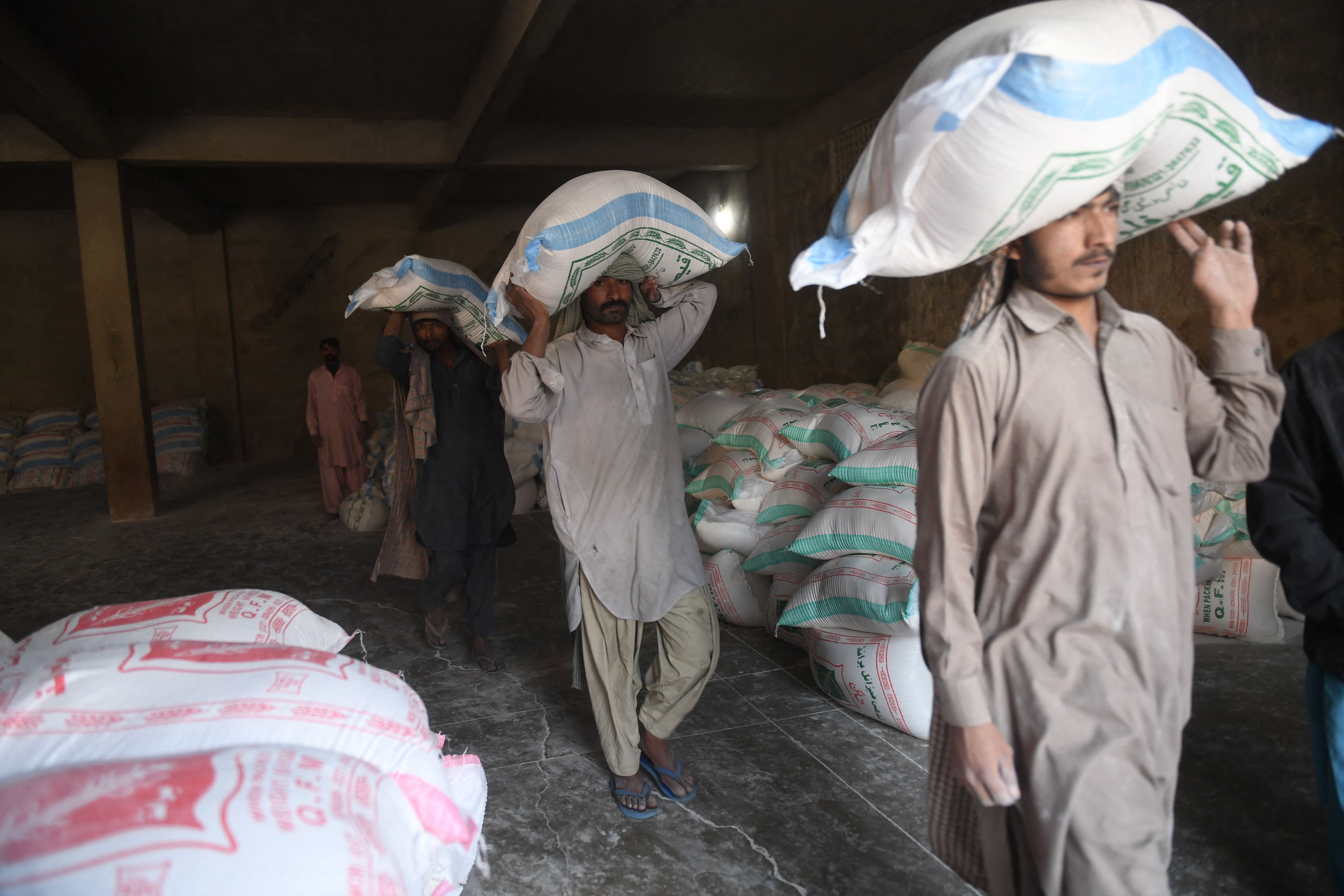 Labourers load sacks of wheat flour at a market in Karachi on January 20, 2020. (AFP)