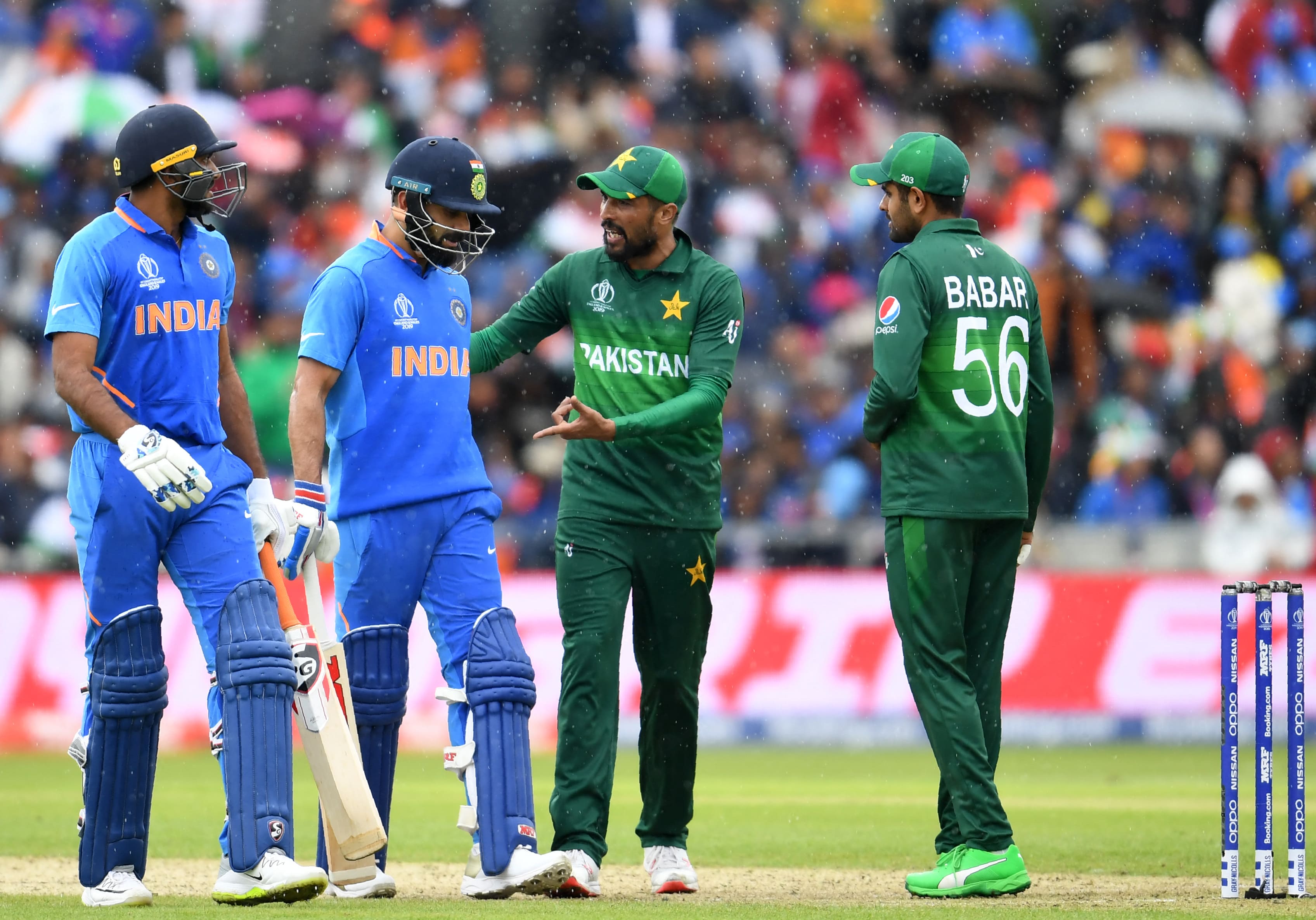In this file photo taken on June 16, 2019, Pakistan's Mohammad Amir (2R) and teammate Babar Azam (R) speak with India's captain Virat Kohli (C) and India's Vijay Shankar (L) as they walk back to the pavilion as rain stops play during the 2019 Cricket World Cup group stage match between India and Pakistan at Old Trafford in Manchester, northwest England. (AFP)