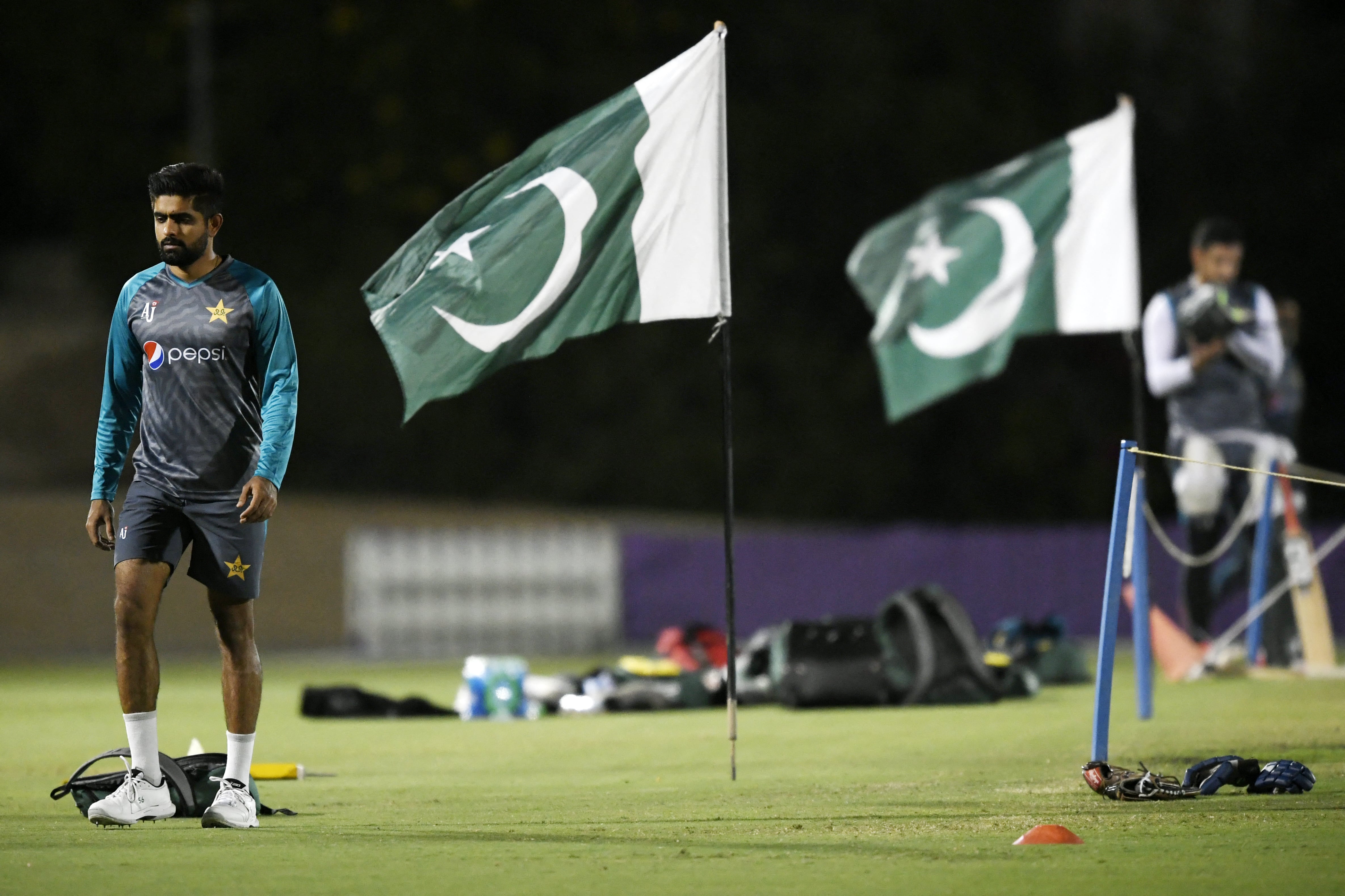 Pakistan's captain Babar Azam (L) walks past national flags during a training session at the ICC cricket academy ground in Dubai on October 19, 2021. (AFP)