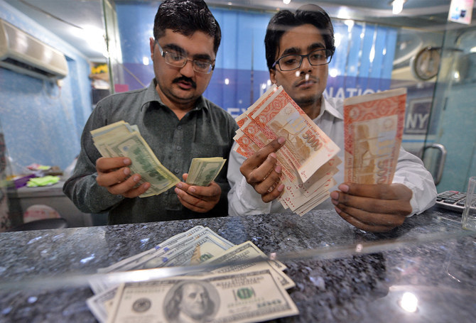 Money dealers counts Pakistani rupees (R) and US dollars at a currency exchange in Islamabad, Pakistan, on March 12, 2014. (AFP/File)