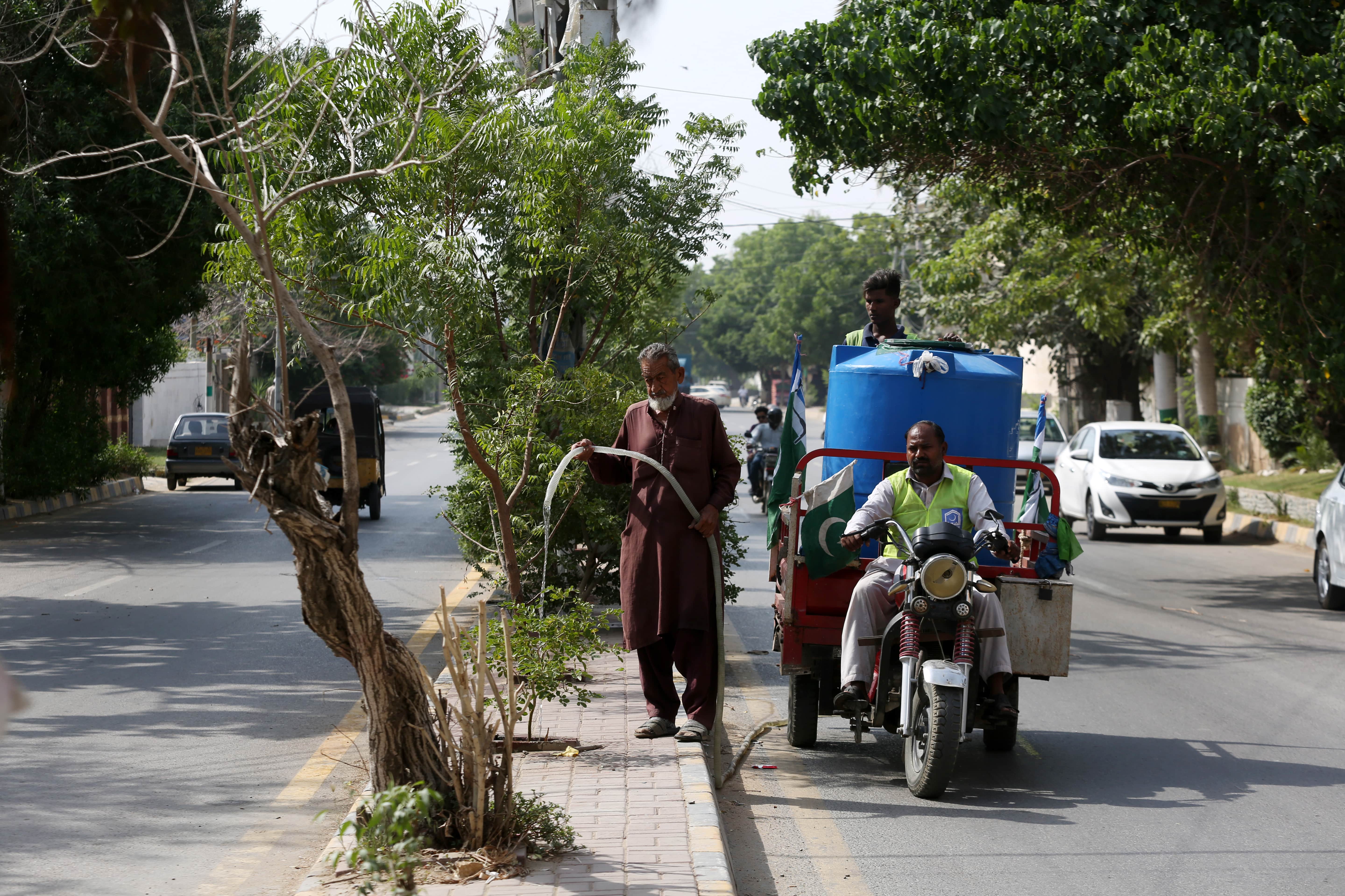 69-year-old gardener Sabir Gul waters plants at Tipu Sultan Road in Karachi, Pakistan, on October 26, 2021 (AN Photo)