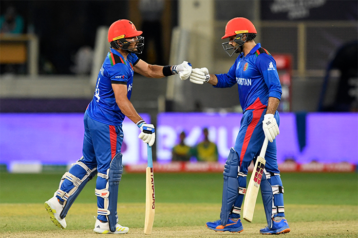 Afghanistan's Gulbadin Naib (L) and captain Mohammad Nabi bump their fists during the ICC men’s Twenty20 World Cup cricket match between Afghanistan and Pakistan in Dubai on October 29, 2021. (AFP)