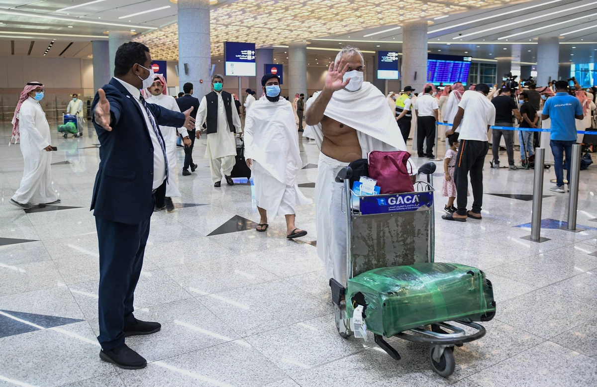 Mask-clad Pakistani travellers arriving to Saudi Arabia to perform the year-round Umrah pilgrimage, walk with their luggage at King Abdulaziz International Airport in the Red Sea coastal city of Jeddah on November 30, 2020. (AFP/ File)