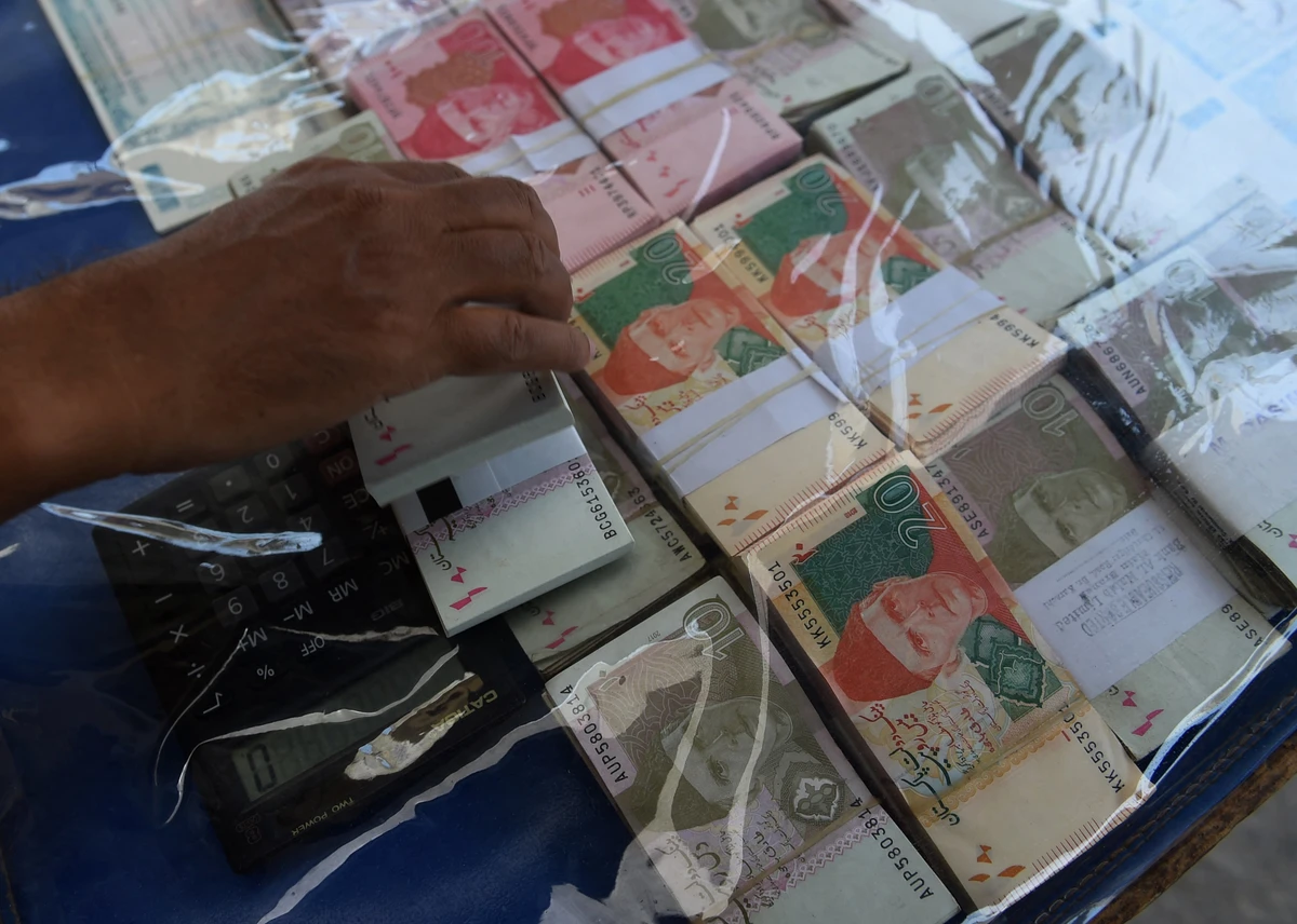 A currency exchange vendor adjusts Pakistani currency notes as he waits for customers on a street in Karachi on May 13, 2019. (AFP/ File)