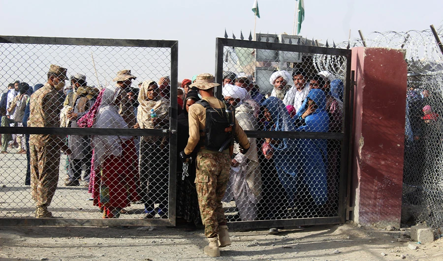 A Pakistani soldier holds a gate as Afghan and Pakistani people wait to enter Afghanistan through the Pakistan-Afghanistan border crossing point in Chaman on August 27, 2021. (AFP)