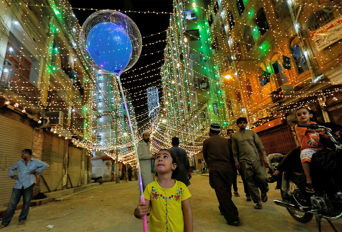 A girl with balloons walks on the eve of Eid-e-Milad-ul-Nabi, the birth anniversary of the Prophet Mohammad, in Karachi, Pakistan, on October 18, 2021. (REUTERS)