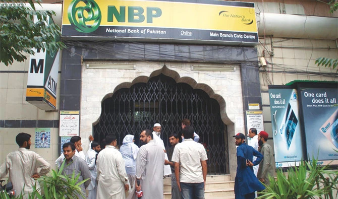This undated photo shows people standing outside the building of National Bank of Pakistan. (APP)