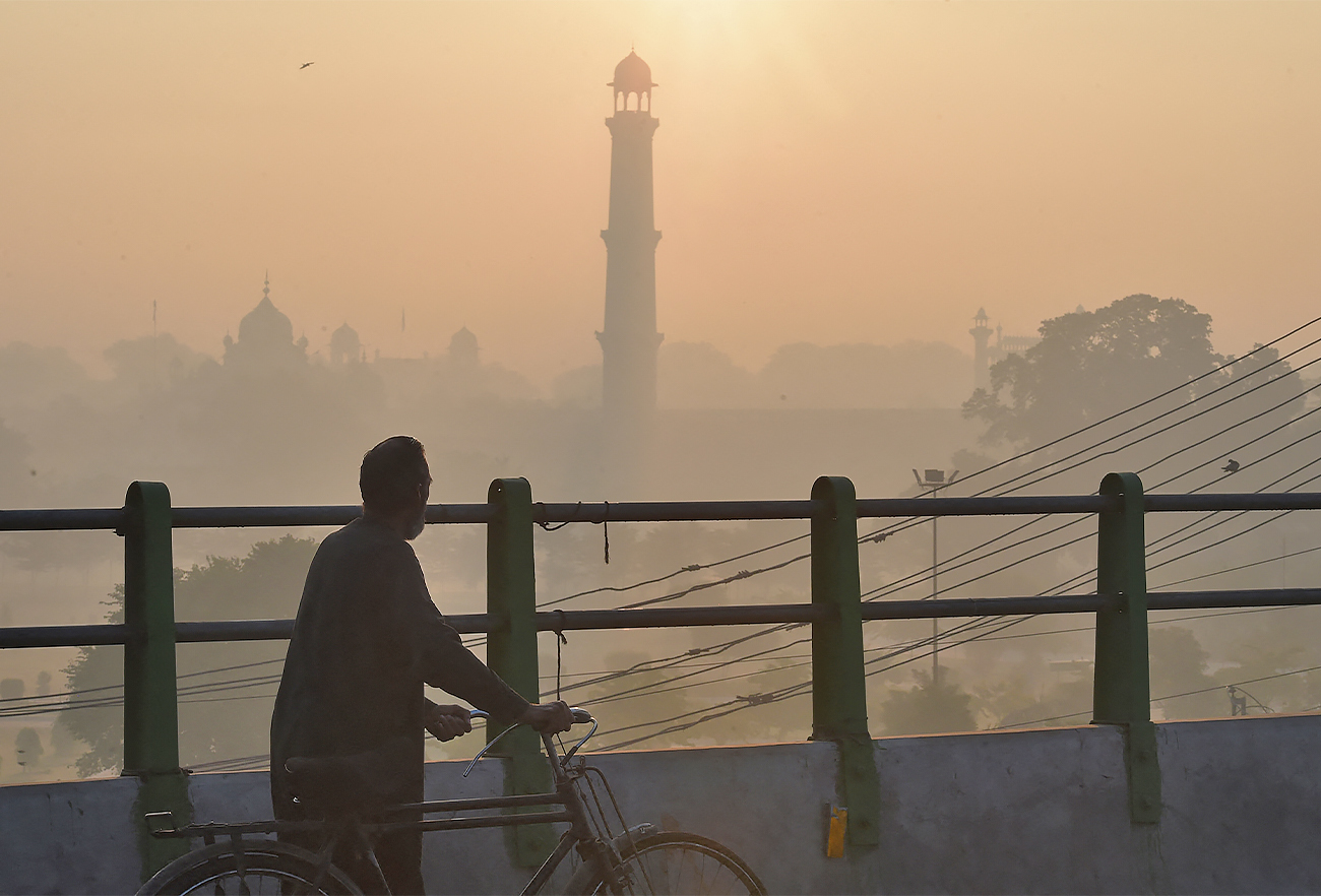 A man walks with a bicycle along a bridge amid heavy smog conditions near Badshahi Mosque in Lahore, Pakistan, on December 6, 2019. (AFP/File)