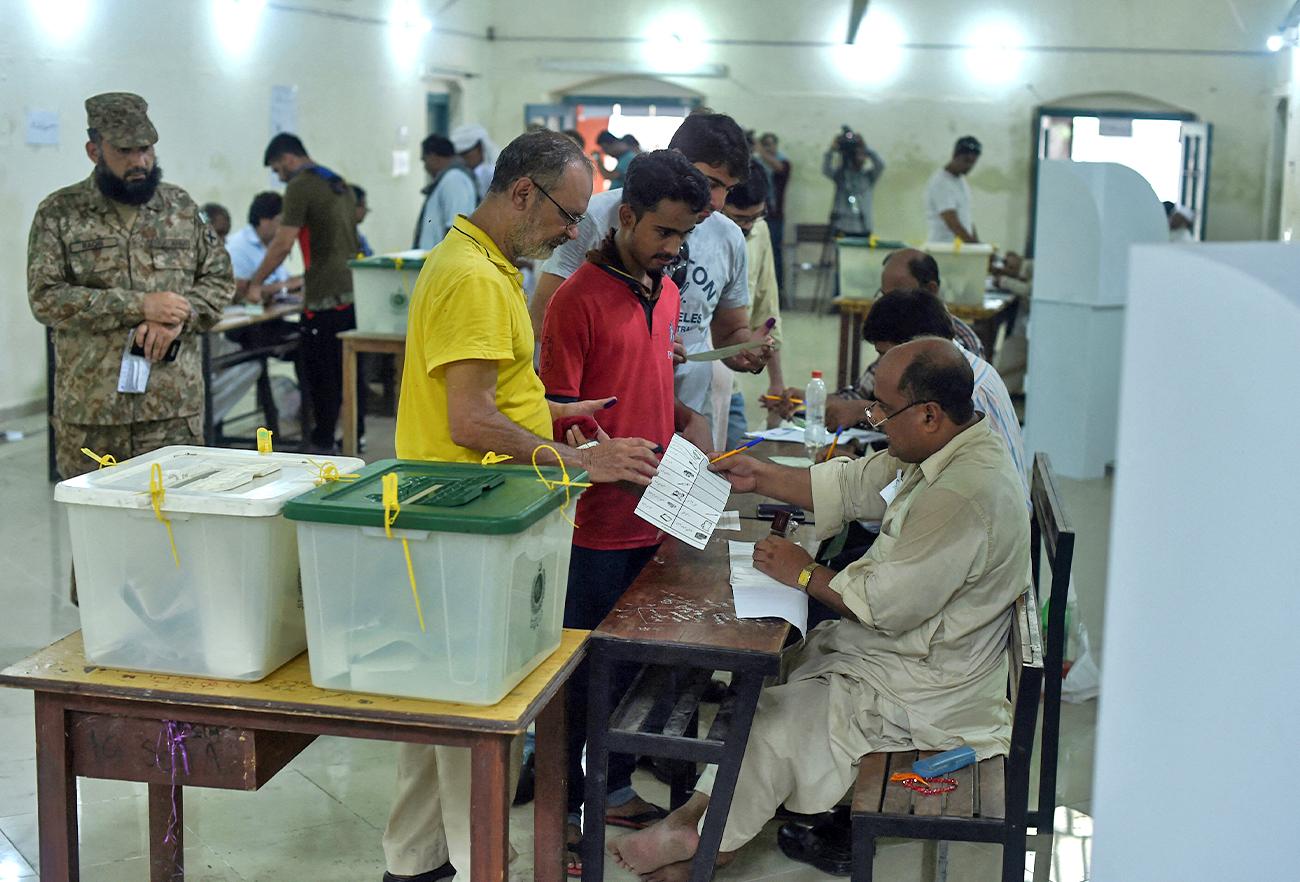 Pakistani men line up as election officials check their ballot papers during voting in Pakistan's general election at a polling station in Lahore, Pakistan, on July 25, 2018. (AFP/File)