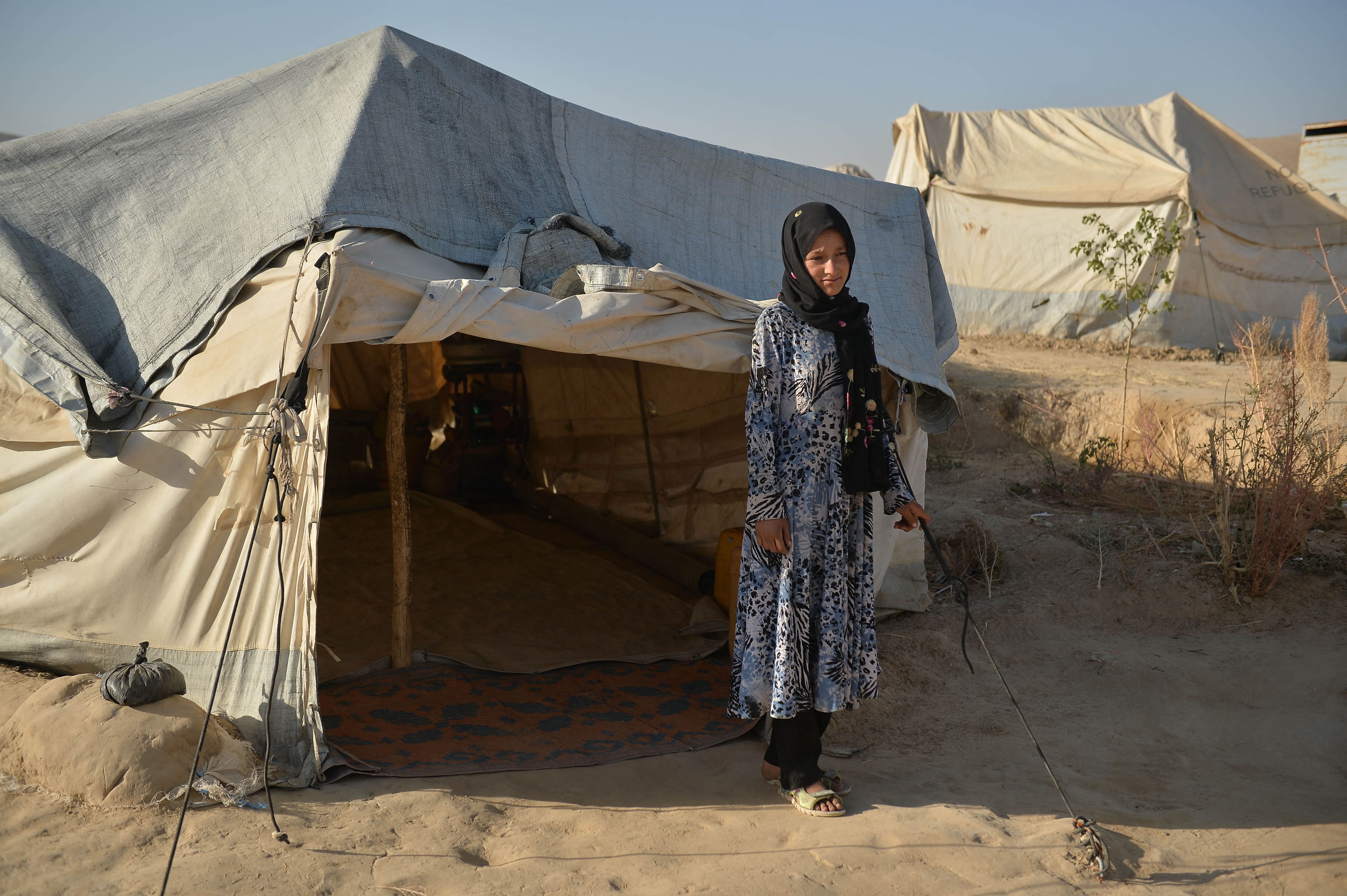 This picture taken on October 17, 2021 shows Habibeh, a girl which lives with her mother but should have gone to join her future spouse's family a month ago, standing in front of her tent at the Zaimat Internally Displaced People (IDP) camp in Qala-i-Naw, Badghis Province. (AFP)