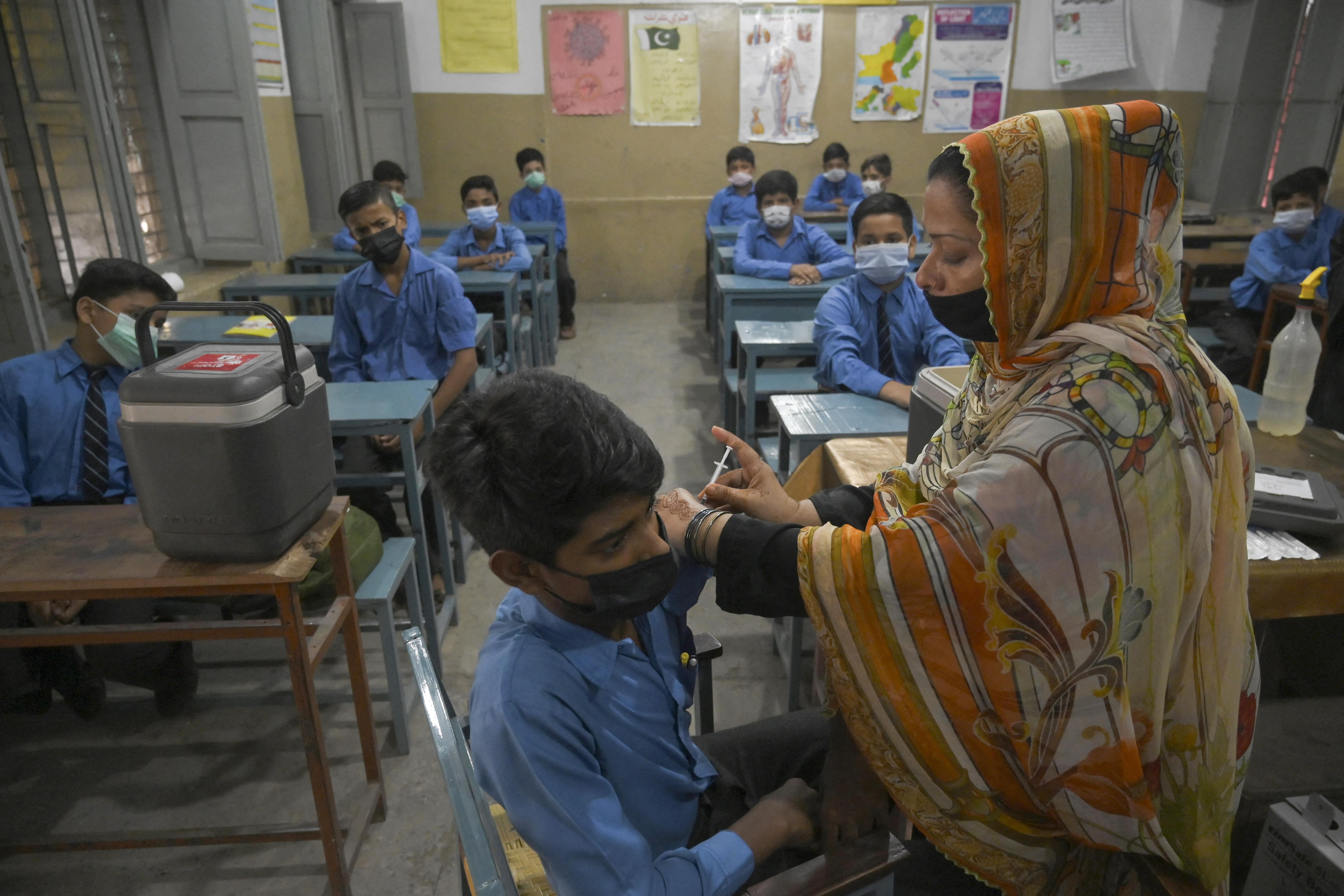 A health worker inoculates a student with a dose of the Pfizer vaccine againsts the Covid-19 coronavirus at a school in Lahore on September 30, 2021. (AFP)