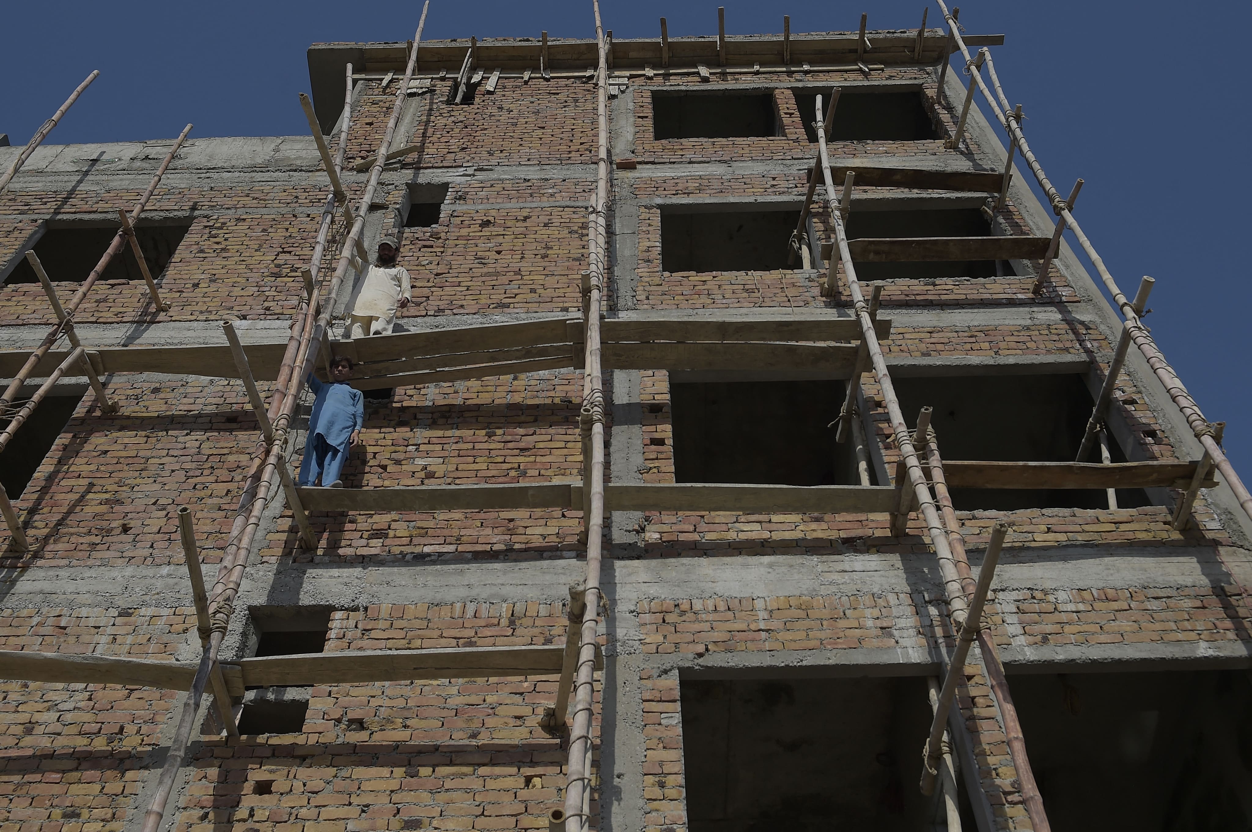 Labourers work on an under construction house on the outskirts of Islamabad on June 14, 2020. (AFP)