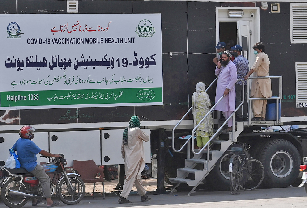 People wait for their turn to get a dose of a vaccine against the coronavirus outside a mobile vaccination health unit in Lahore, Pakistan, on July 7, 2021. (AFP/File)