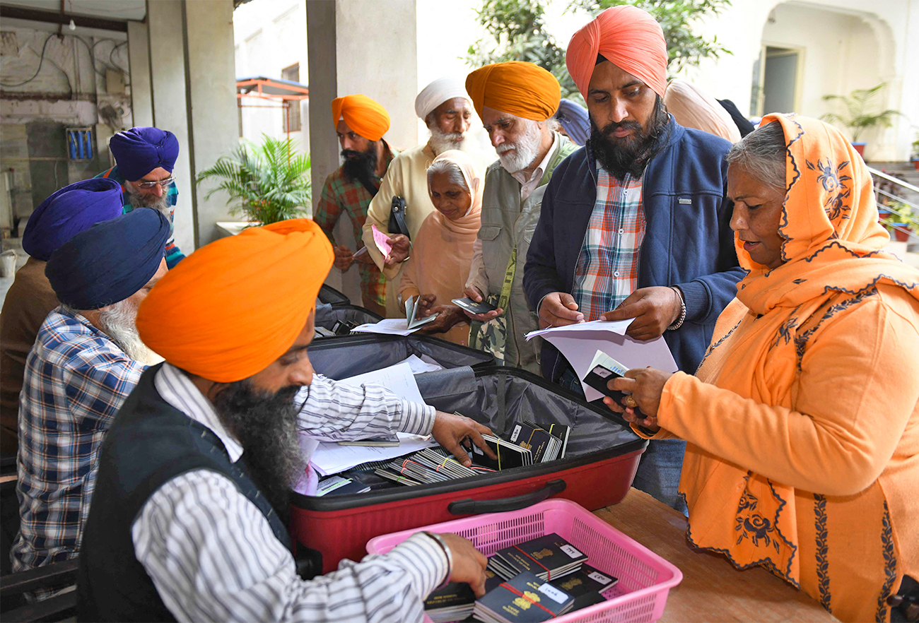 Sikh pilgrims collect their passports from a Shiromani Gurdwara Parbandhak Committee (SGPC) official in Amritsar on November 16, 2021 as they travel to Pakistan to celebrate the 552nd birth anniversary of Sri Guru Nanak Dev. (AFP)