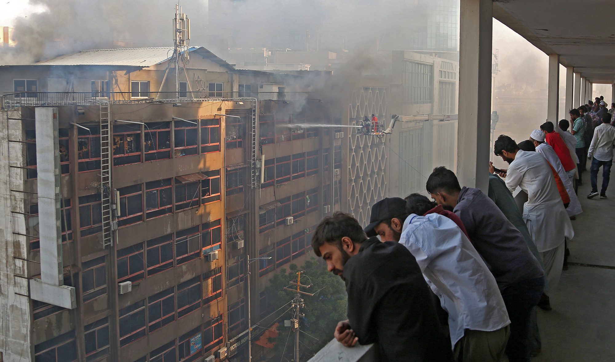 People watch as firefighters put out flames that engulfed the Queen Victoria Market in Karachi, Pakistan, on Wednesday, November 17, 2021. (AN Photo by S.A. Babar)