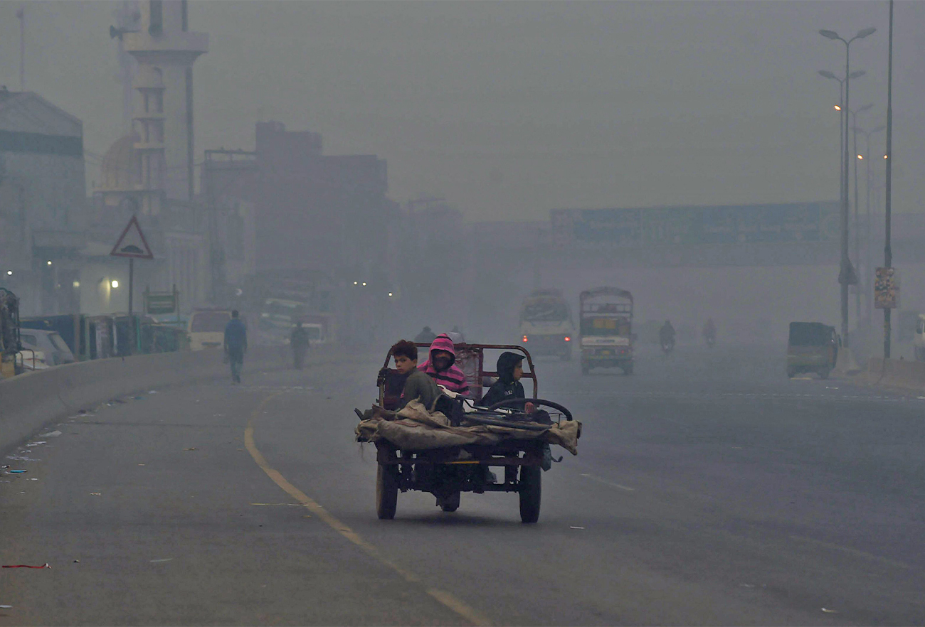 People commute along a street amid heavy smoggy conditions in Lahore, Pakistan, on November 18, 2021. (AFP)