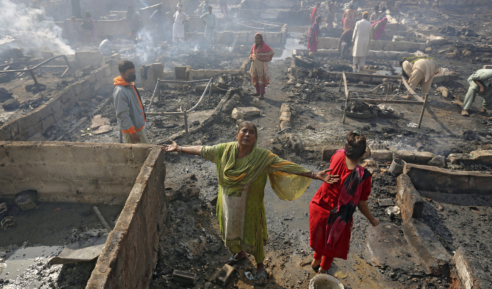 A woman grieves while she and others collect their belongings in Karachi, Pakistan on November 20, 2021, following a fire that gutted hut homes. (AP)