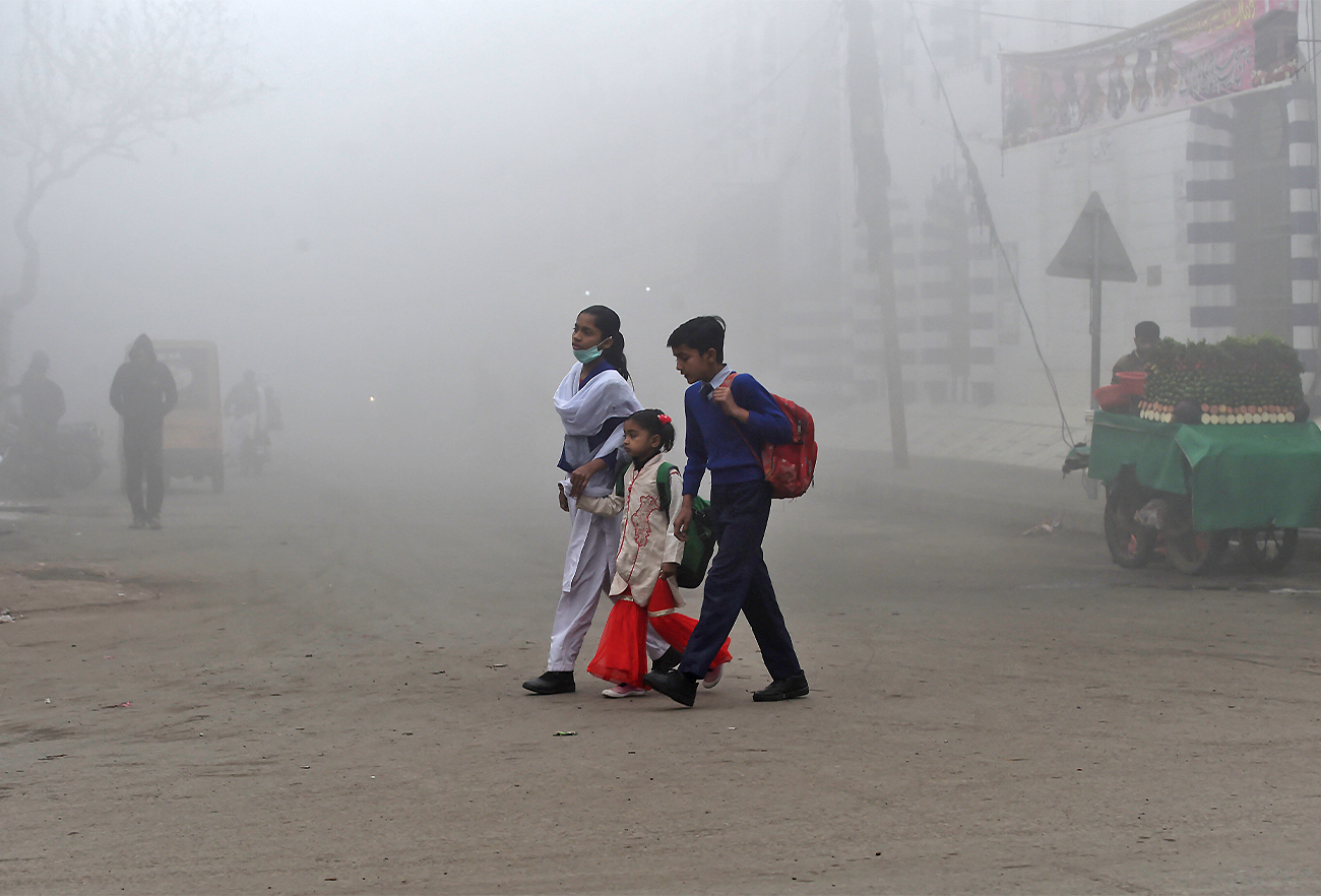Children cross a street on their way to school amid heavy smog conditions in Lahore, Pakistan, on February 12, 2021. (AFP)