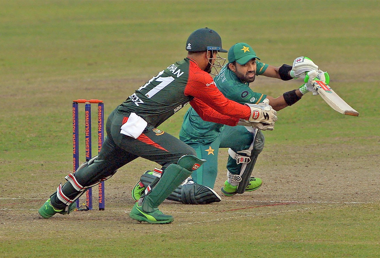 Pakistan's Mohammad Rizwan (R) plays a shot as Bangladesh's wicketkeeper Nurul Hasan tries to catch the ball during the third Twenty20 cricket match at Sher-E-Bangla National Cricket Stadium in Dhaka on November 22, 2021. (AFP)