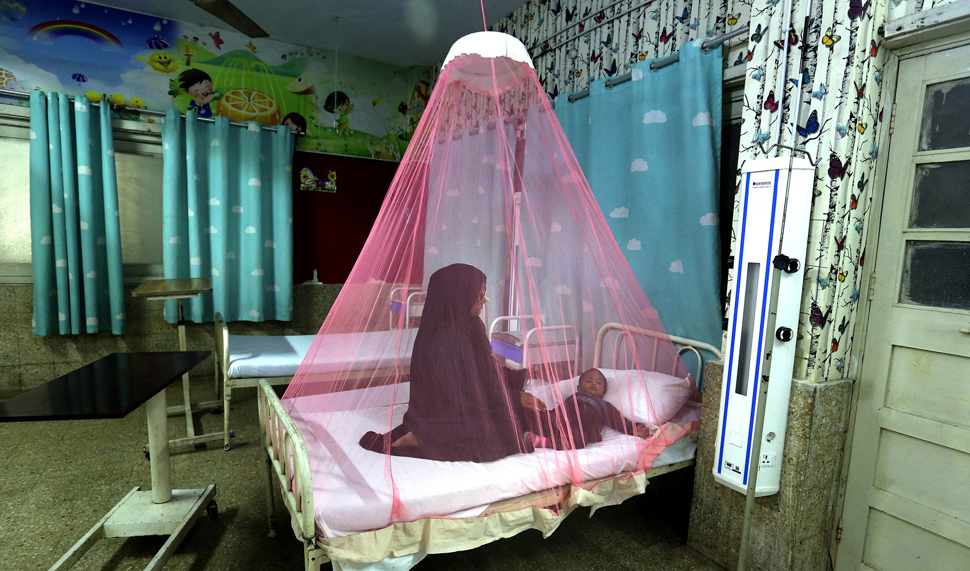 A mother takes care of her son who is suffering from dengue fever in a hospital in Karachi, Pakistan, on November 22, 2021. (AP)