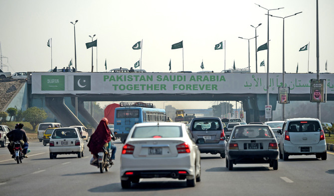 Pakistani commuters drive their vehicles under a banner welcoming Saudi Arabian Crown Prince Mohammed bin Salman displayed on a bridge, ahead of his arrival, in Islamabad on Feb. 15, 2019. (AFP)
