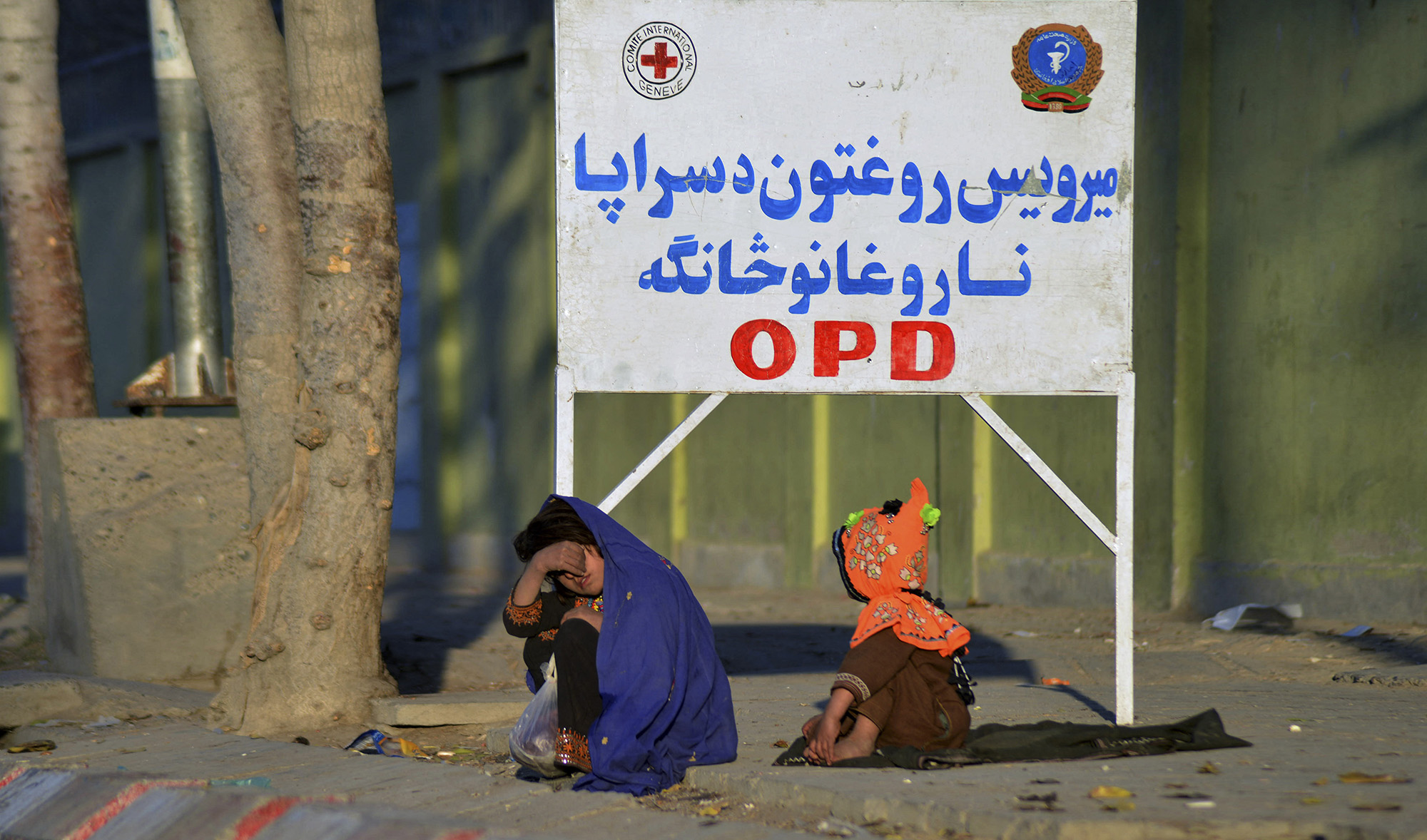 Girls sit on a footpath in front of Mirwais Hospital in Kandahar, Afghanistan, on November 25, 2021. (AFP/File)
