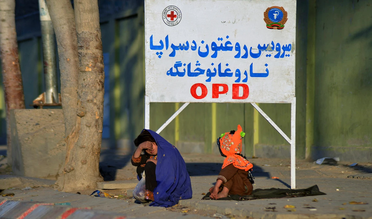 Girls sit on a footpath in front of Mirwais Hospital in Kandahar, Afghanistan, on November 25, 2021. (AFP/File)
