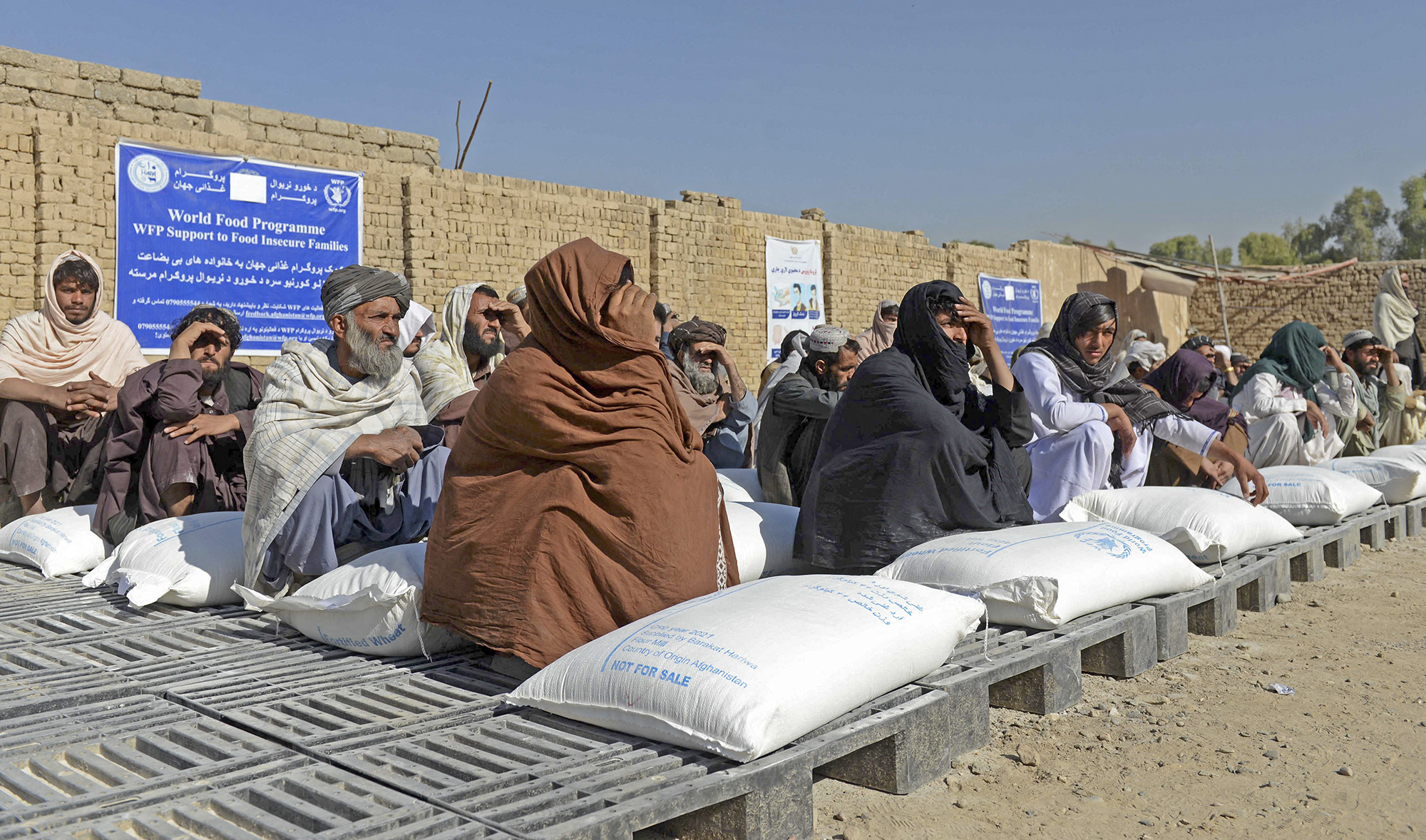 Afghan people sit besides sacks of food grains distributed as an aid by the World Food Programme (WFP) in Kandahar on October 19, 2021. (AFP/File)