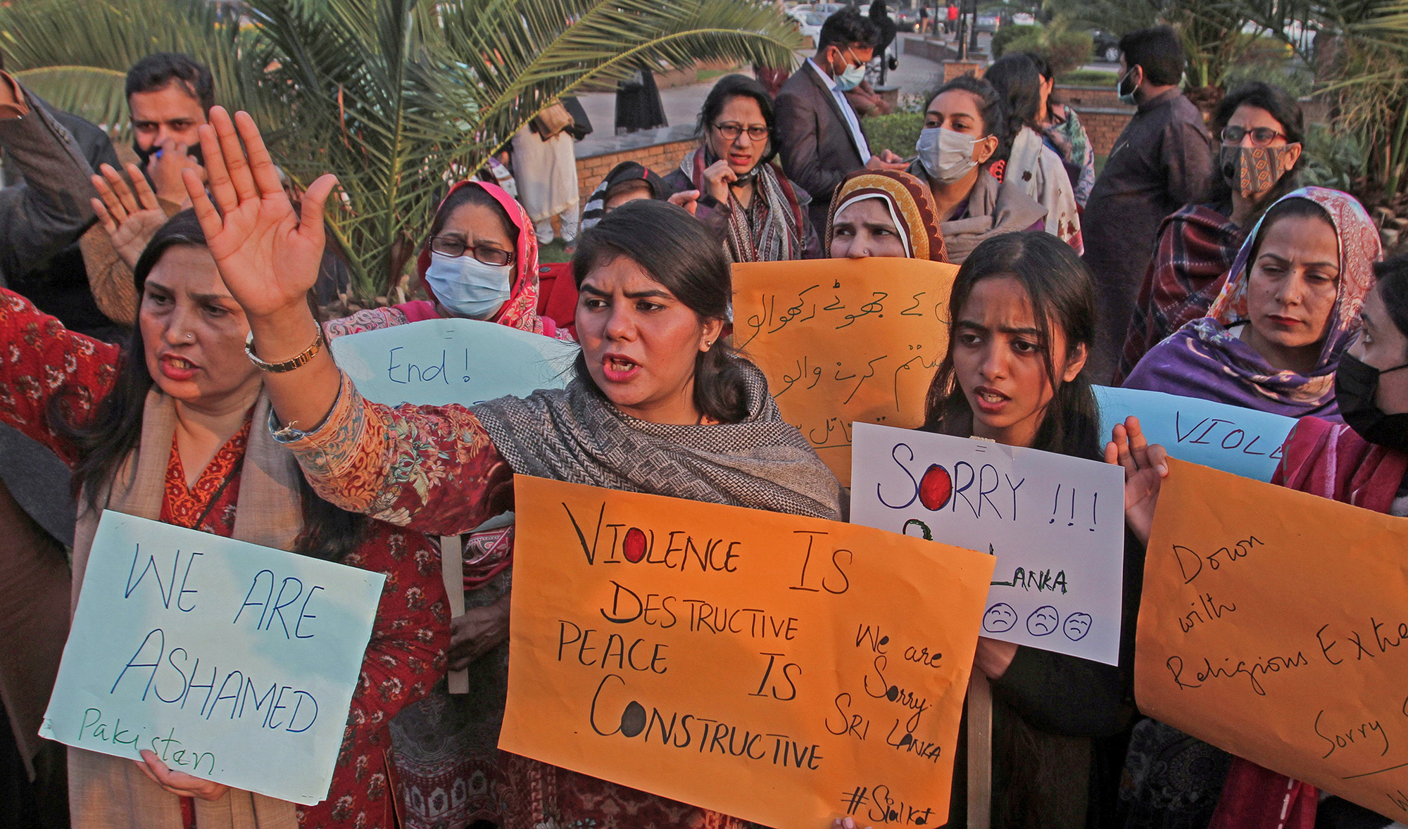 People carry signs as they chant slogans, condemning the lynching of the Sri Lankan manager of a garment factory after an attack on the factory in Sialkot, during a protest in Lahore, on December 4, 2021. (REUTERS)