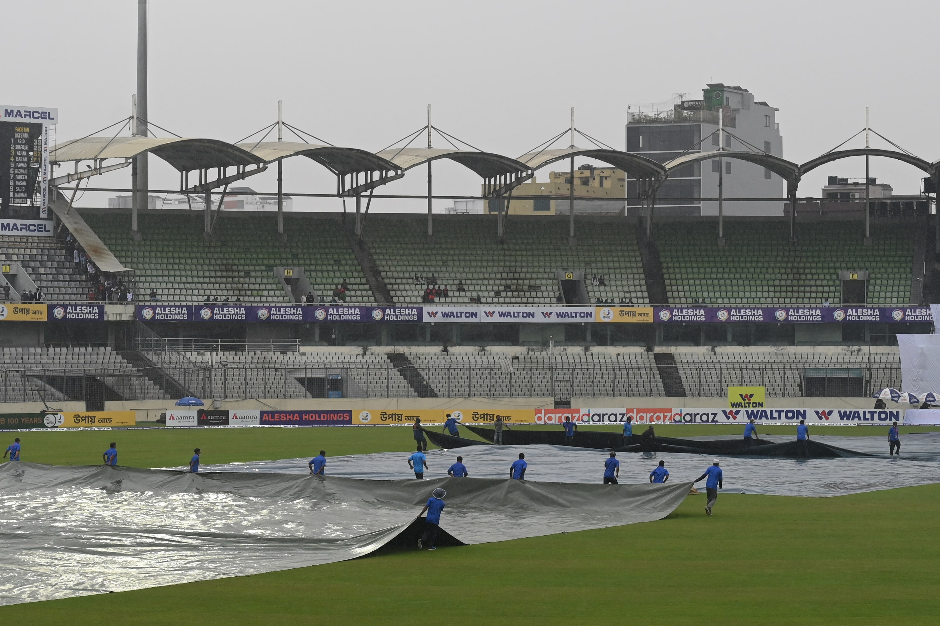 Groundstaff cover the field as it starts to rain on the second day of the second Test cricket match between Bangladesh and Pakistan at the Sher-e-Bangla National Cricket Stadium in Dhaka on December 5, 2021. (AFP)