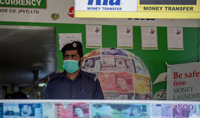 A security guard wearing a facemask amid concerns over the spread of the COVID-19 novel coronavirus stands guard outside a currency exchange shop in Rawalpindi on March 18, 2020. (AFP/ File)