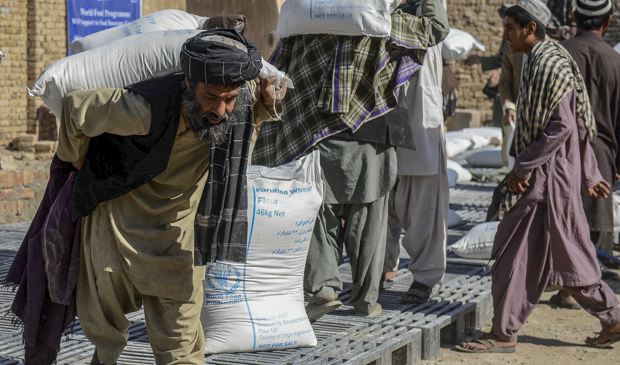 Afghan people carry sacks of food grains distributed as an aid by the World Food Programme (WFP) in Kandahar, Afghanistan, on October 19, 2021. (AFP/File)