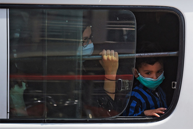 A mother and son wearing facemask sit in a local transport outside a bus station in Islamabad on April 10, 2021. (AFP)