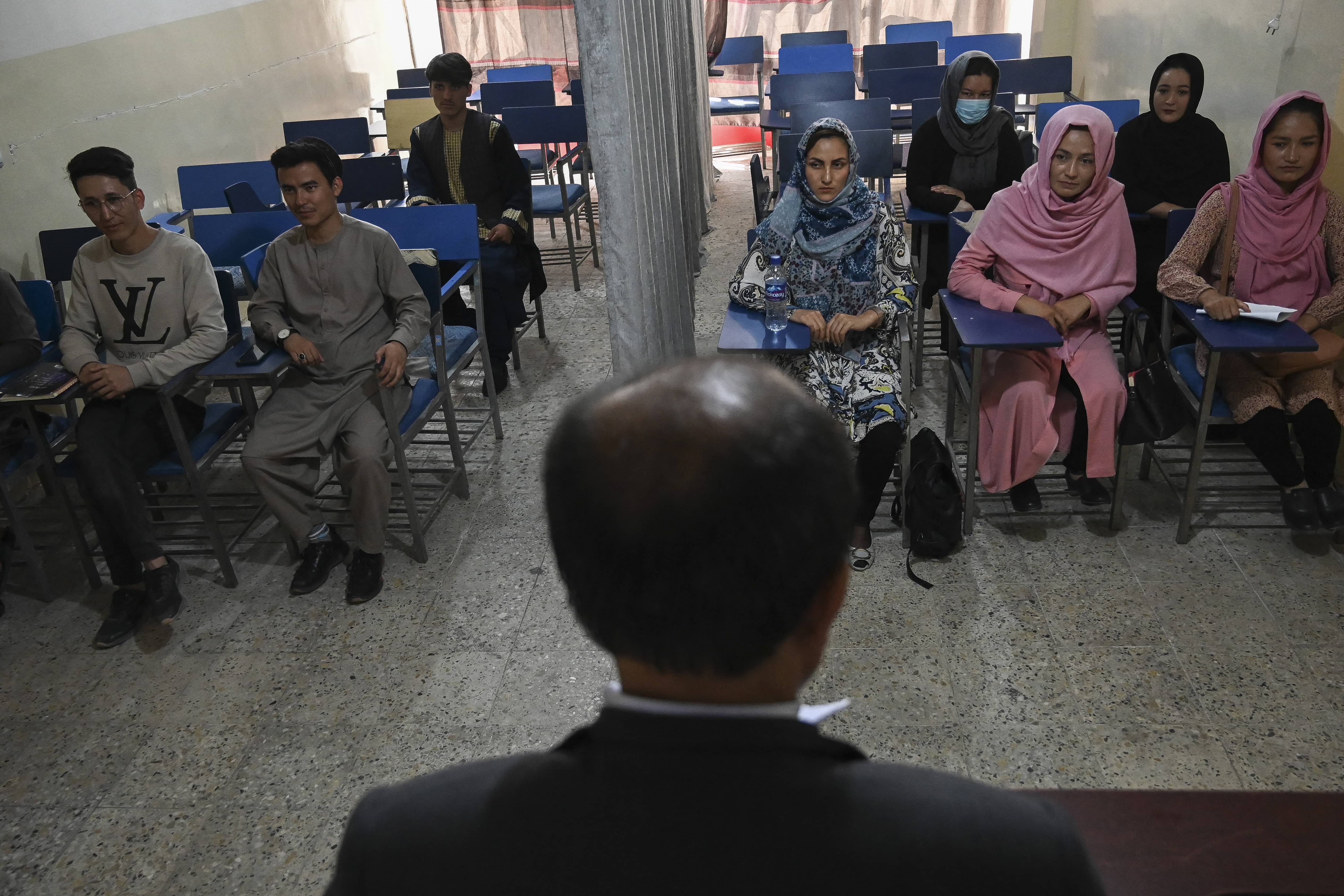 Students attend a class bifurcated by a curtain separating males and females at a private university in Kabul on September 7, 2021, to follow the Taliban's ruling. (AFP)
