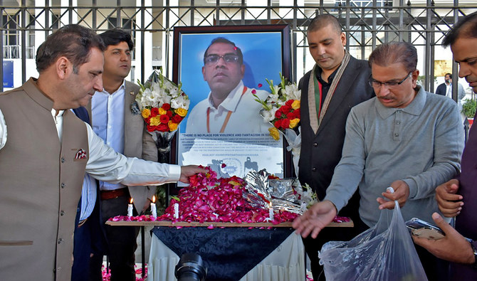 Businessmen put candles and rose petals next to the portrait of Priyantha Kumara Diyawadana, a Sri Lankan national who was lynched by a mob in Sialkot, Pakistan, as they pay tribute to him outside the Sialkot Chamber of Commerce and Industry on December 4, 2021. (AP)