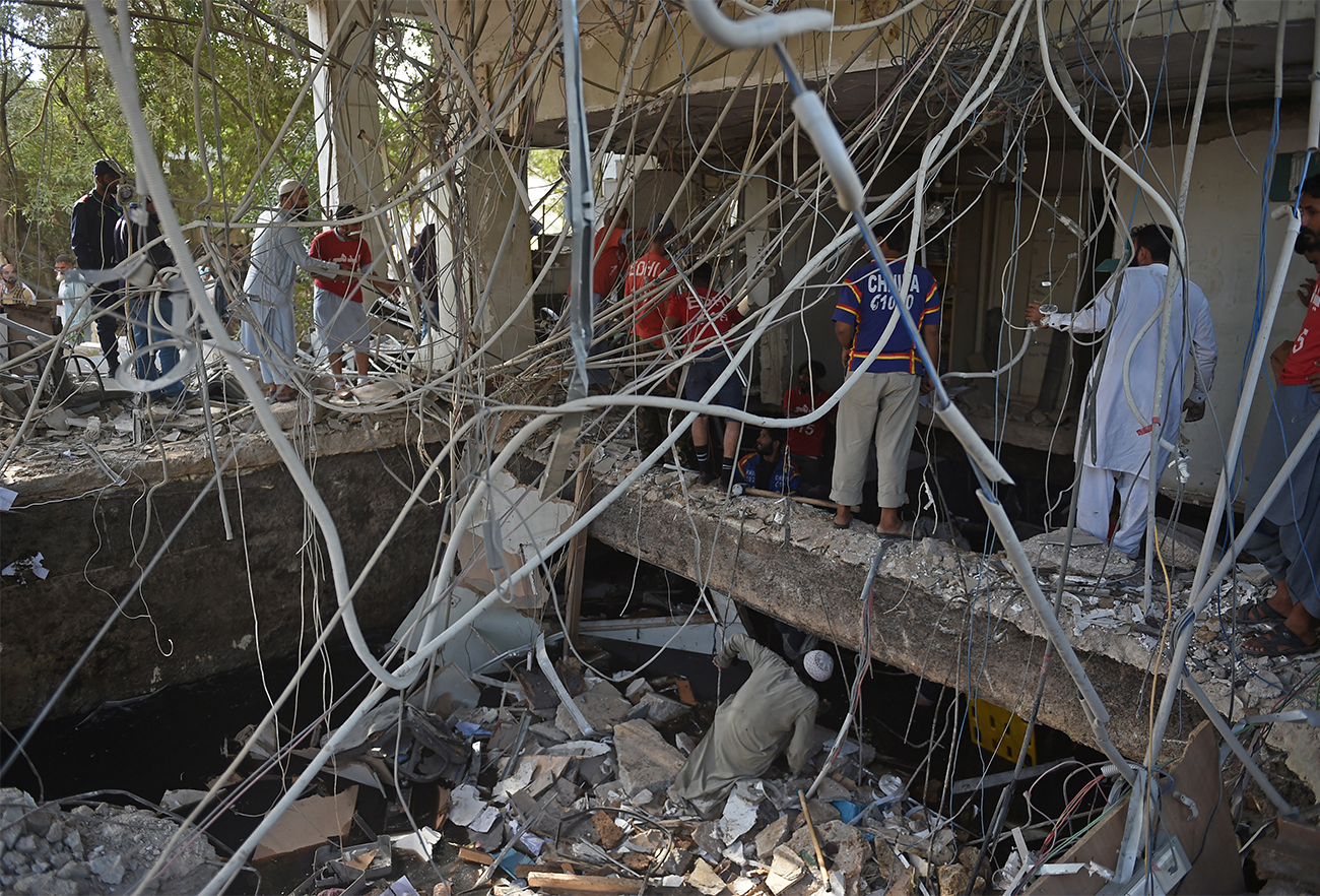 Rescuers gather amid the debris of a bank building that collapsed after a gas blast in Karachi, Pakistan, on December 18, 2021, as at least 12 people were killed and several more injured. (AFP)