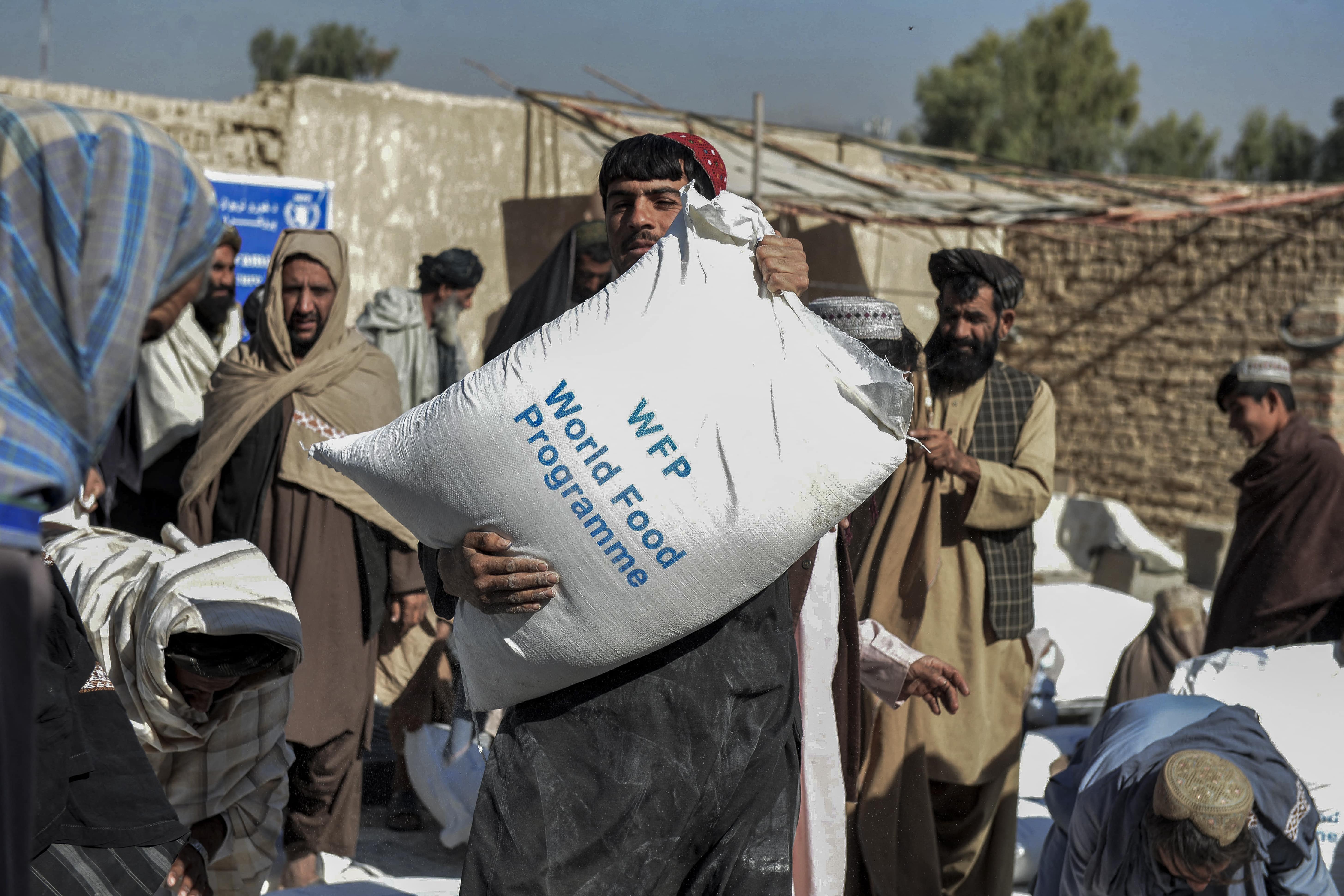 Afghans carry sacks of grains distributed as aid by the World Food Programme in Kandahar, Afghanistan on October 19, 2021. (AFP/File)