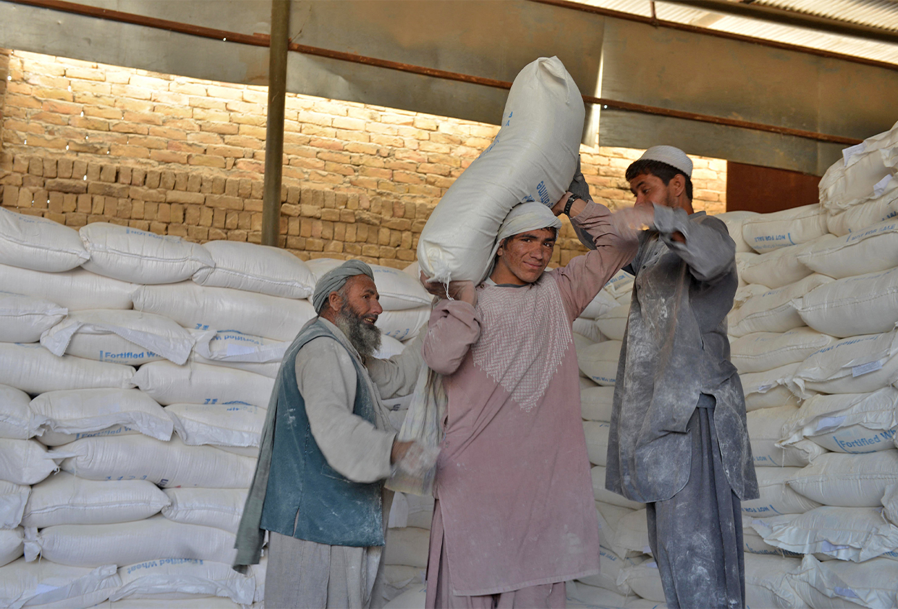 Afghan workers unload sacks of food grains from a pile for distribution as an aid by the World Food Programme (WFP) in Kandahar, Afghanistan, on October 19, 2021. (AFP/File)