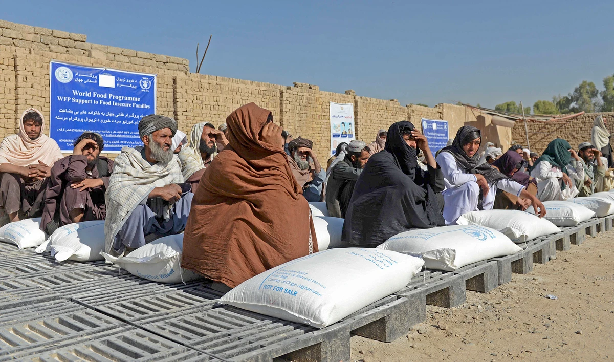 Afghan people sit besides sacks of food grains distributed as an aid by the World Food Programme (WFP) in Kandahar on October 19, 2021. (AFP/File)