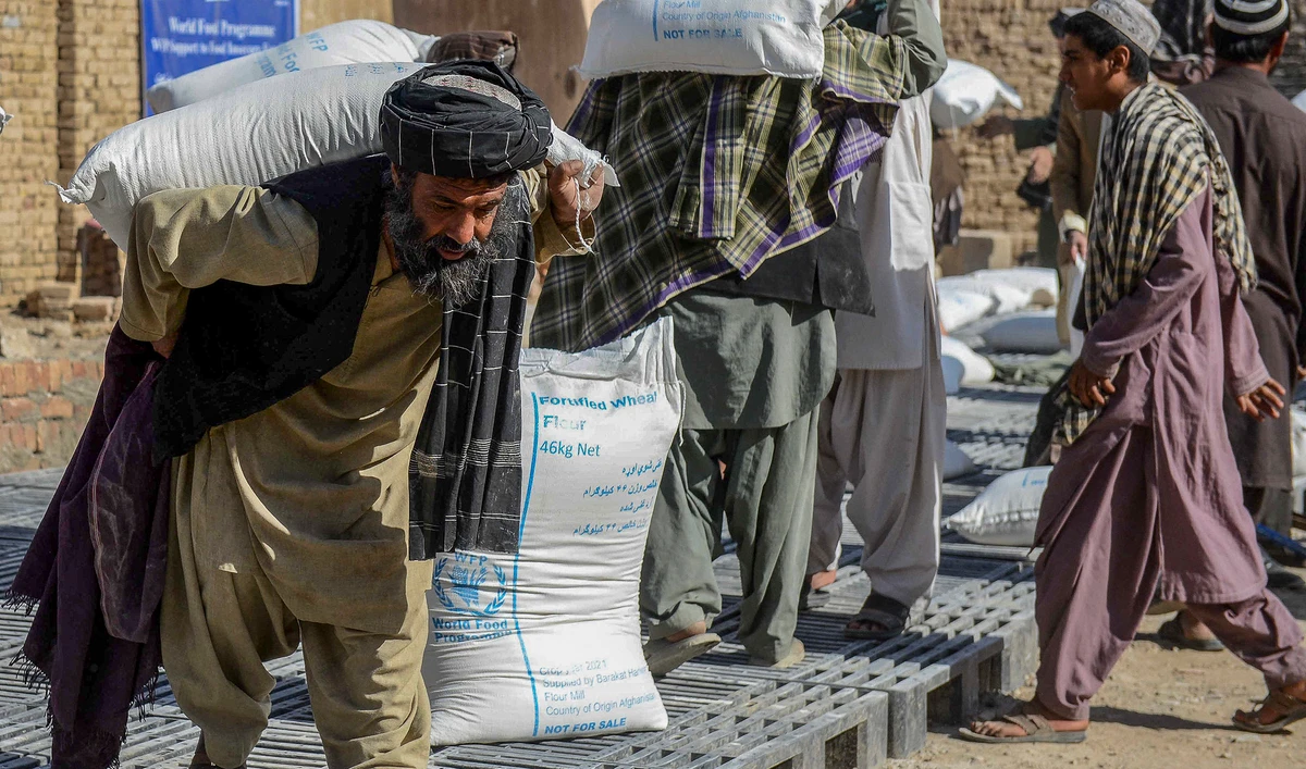 Afghan people carry sacks of food grains distributed as an aid by the World Food Programme (WFP) in Kandahar, Afghanistan, on October 19, 2021. (AFP/File)