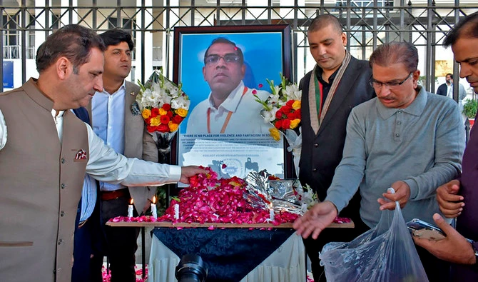 Businessmen put candles and rose petals next to the portrait of Priyantha Kumara Diyawadana, a Sri Lankan national who was lynched by a mob in Sialkot, Pakistan, as they pay tribute to him outside the Sialkot Chamber of Commerce and Industry on December 4, 2021. (AP)